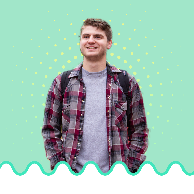 A male student smiling towards the left on a green background with a yellow radiant burst behind him