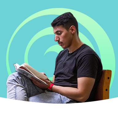 A male student reading a book on a teal background with a green swirl behind him