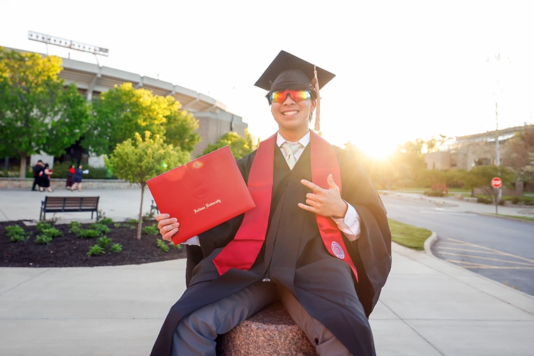 Graduate student posing with their diploma.