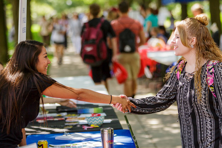 Two female students shaking hands.